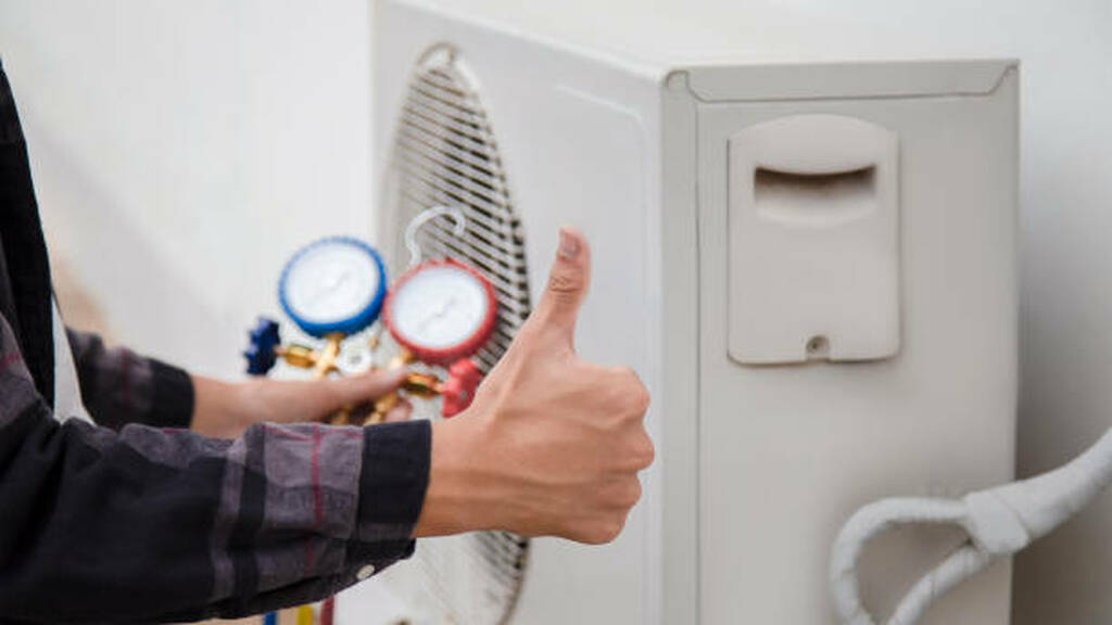 Unlock Savings: The Key Benefits of an HVAC Tune-Up Technician giving a thumbs up next to a heat pump with pressure gauges, emphasizing HVAC maintenance and efficiency improvements.