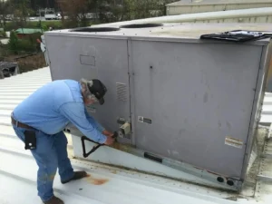 Technician adjusting an HVAC unit on a rooftop.